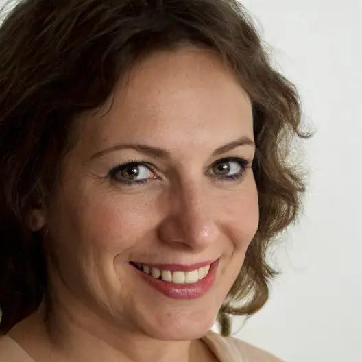 Foto primer plano tres cuarto perfil, mujer de cabello ondulado, sonriendo